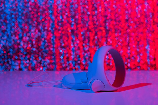 Close-up photo of a stack of wireless silent disco headphones, each with glowing LED lights in various colors. The headphones are neatly arranged, showcasing the clean and modern design.