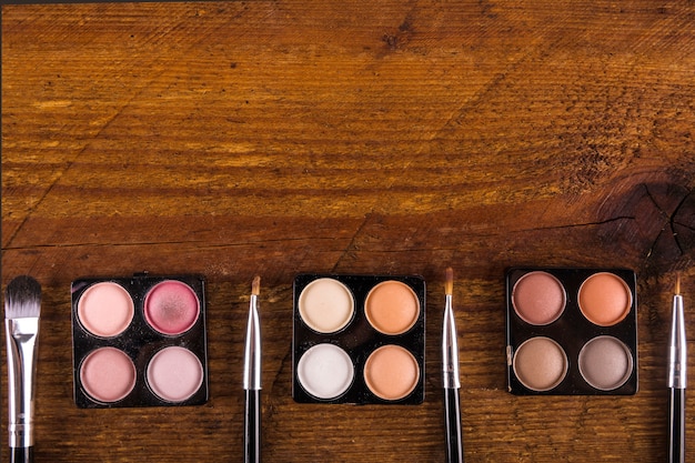 Close-up of various makeup products laid out on a table, including foundation, concealer, blush, mascara, and a multi-use stick. Products are arranged neatly, suggesting a planned, efficient routine.