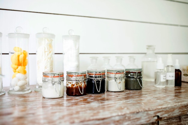 A clean, well-organized workstation with various small glass bottles filled with homemade skincare ingredients like aloe vera gel, rose water, and essential oils; labels are neatly adhered to each bottle, indicating the contents and date; sterile measuring spoons and a small digital scale are also visible; focus on the sense of hygiene and precision.