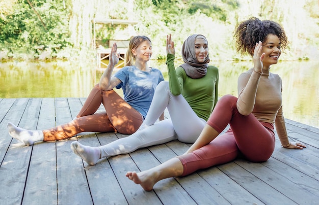 A group of women are stretching together after a walk in a park. They are laughing and talking, showing a sense of community and shared enjoyment. The sun is setting in the background, casting a warm glow on the scene.