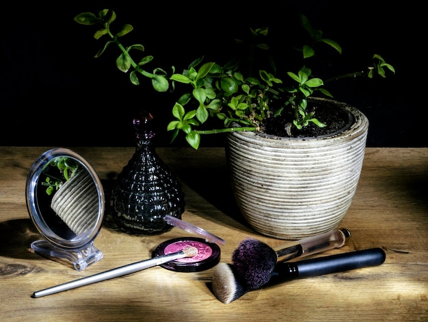A close-up shot of a variety of makeup products neatly arranged on a vanity, with a blurred background showing a person's hands reaching for a brush, highlighting the tactile and visually appealing nature of beauty routines.
