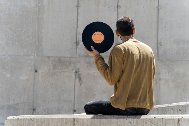A close-up shot of a person carefully placing a vinyl record on a vintage turntable. The turntable is wooden with chrome accents, and the record sleeve is visible in the background, showcasing a classic album cover. The lighting is warm and inviting.