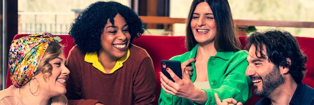 A close-up of a diverse group of people looking at their smartphones, smiling and engaged. The background is blurred and shows various social media logos.