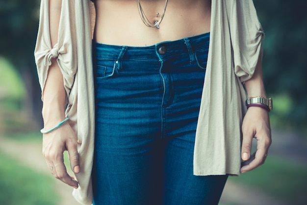 A close-up shot of a model wearing low-rise jeans with a modern twist: a slightly higher rise than the original Y2K style, paired with a minimalist white crop top and delicate gold jewelry, showcasing a sophisticated yet nostalgic look.