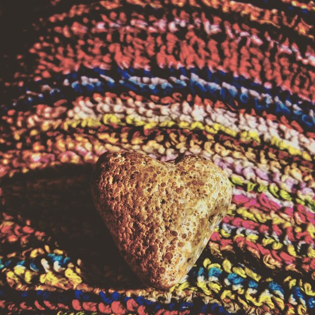Close-up of a textured wool scarf featuring a mustard yellow and teal geometric pattern, casually draped over a wooden chair, with natural light highlighting the interplay of the two colors.