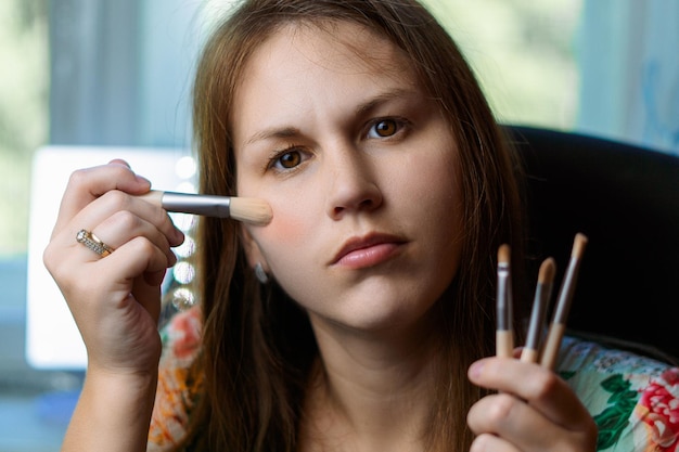 A woman applying a concealer shade that is too light under her eyes, creating a grayish cast and emphasizing dark circles.