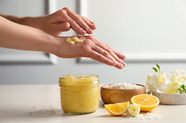 A person's hands gently exfoliating their face with a homemade lemon and honey scrub, with a soft background suggesting a spa setting.