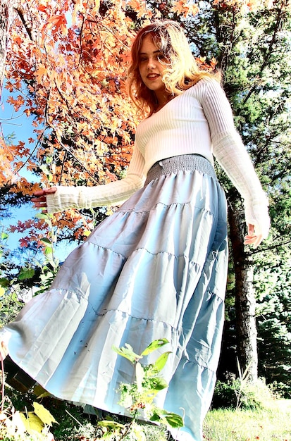 A split-screen image showing a woman in a flowy midi skirt and a simple top; on the left, she wears sandals and a straw hat for a daytime look, and on the right, she wears heels and a statement belt for an evening look.