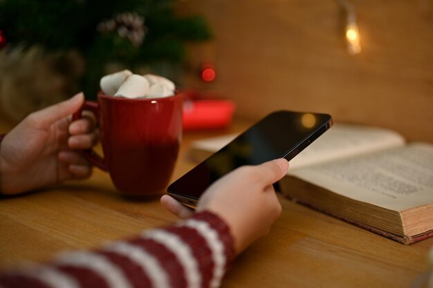 A person's hands holding a smartphone, with a notification showing a new promo code alert. The background is a cozy coffee shop, indicating casual browsing.