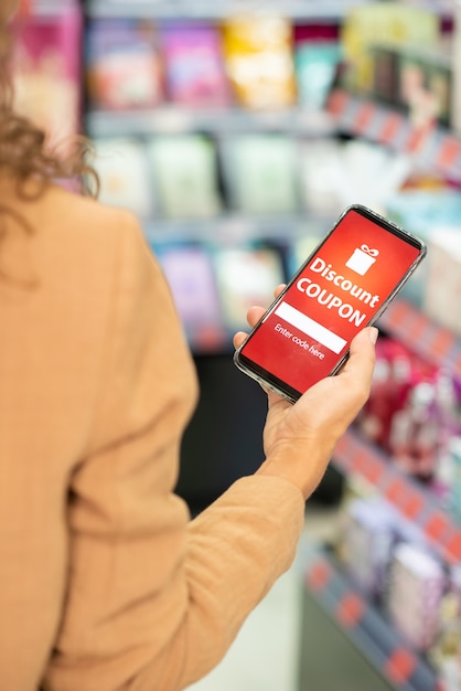 A close-up shot focusing on a mobile phone screen displaying a loyalty program app, showing a user redeeming points for a discount at checkout.