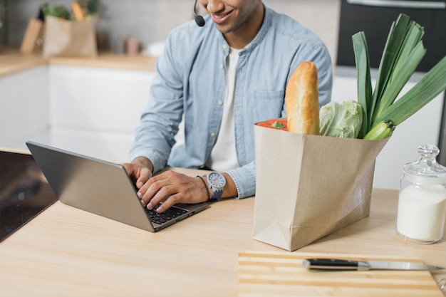 A person sitting at a desk, using a laptop to browse an online grocery store website. The webpage showcases a variety of items for sale, with a prominent display of the 20% cashback offer banner. The scene suggests the convenience and savings associated with online shopping.
