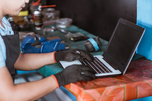 A close-up shot of a technician inspecting a refurbished laptop with specialized tools in a clean, well-lit repair facility. The focus is on the technician's hands and the internal components of the laptop.